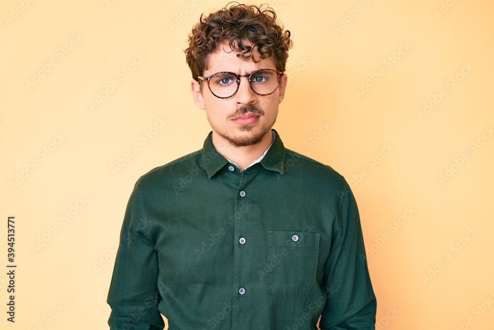 Young caucasian man with curly hair wearing casual clothes and glasses skeptic and nervous, frowning upset because of problem. negative person. Young caucasian man with curly hair wearing casual clothes and glasses skeptic and nervous, frowning upset because of problem. negative person.