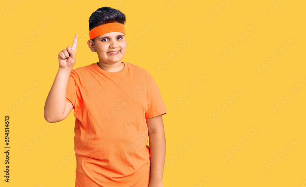 Fototapeta premium Little boy kid wearing sportswear showing and pointing up with finger number one while smiling confident and happy.