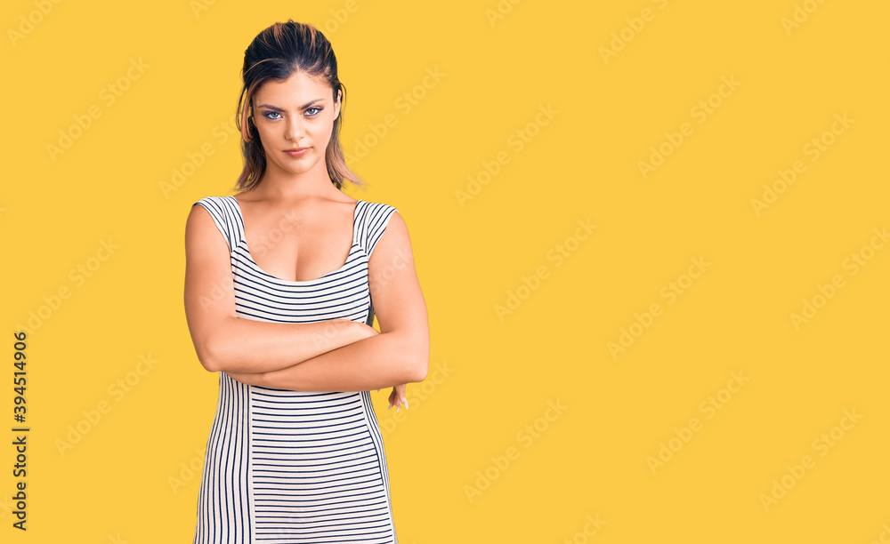 Young beautiful woman wearing casual dress skeptic and nervous, disapproving expression on face with crossed arms. negative person.