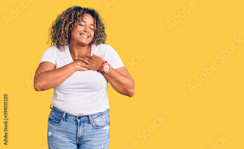 Young african american plus size woman wearing casual clothes smiling with hands on chest with closed eyes and grateful gesture on face. health concept.