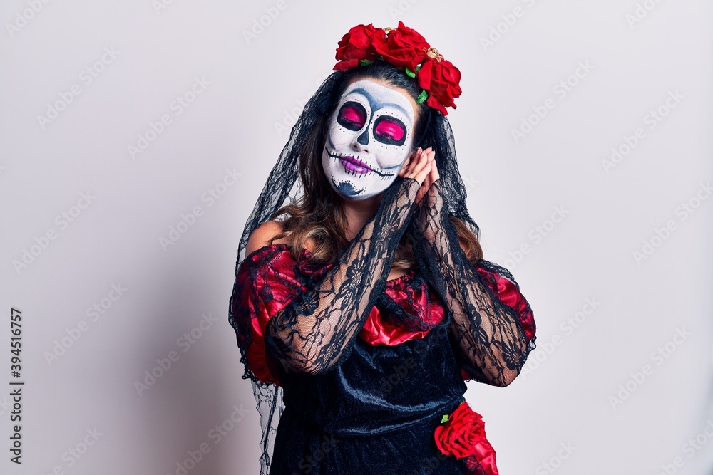 Young woman wearing day of the dead costume over white sleeping tired dreaming and posing with hands together while smiling with closed eyes. Young woman wearing day of the dead costume over white sleeping tired dreaming and posing with hands together while smiling with closed eyes.
