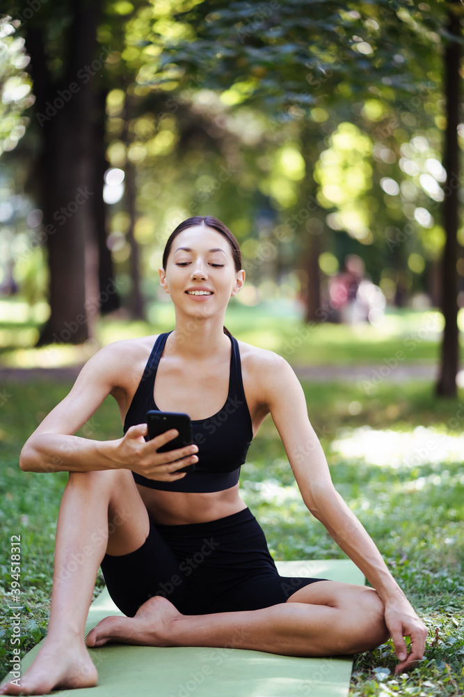 Fitness girl with a smartphone on nature background.