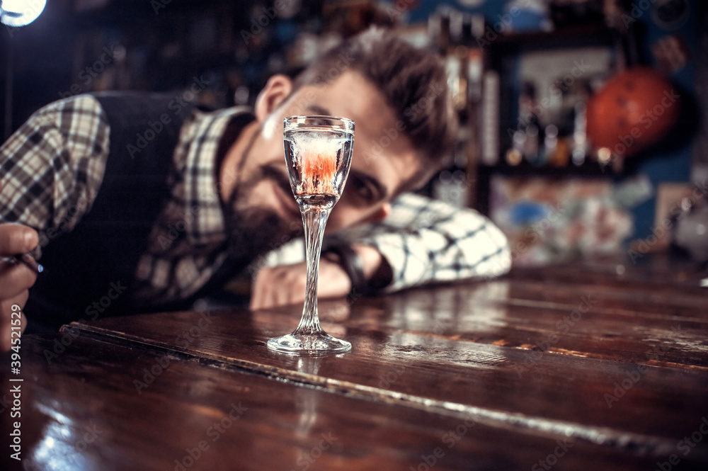 Young bartender makes a cocktail at the bar counter