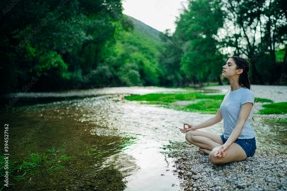 Meditation yoga woman siting at Lotus position on the shore of river.Serenity and yoga practice.Healthy lifestyle.Self isolation in nature.Lockdown beach trip.Mindfulness.Breathing exercise Meditation yoga woman siting at Lotus position on the shore of river.Serenity and yoga practice.Healthy lifestyle.Self isolation in nature.Lockdown beach trip.Mindfulness.Breathing exercise