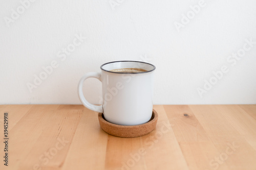 White hot coffee cup on wooden table and white wall with copy space.