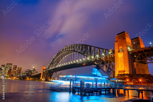 Sydney Harbour Bridge at night with ferry boat crossing and city skyline © jovannig
