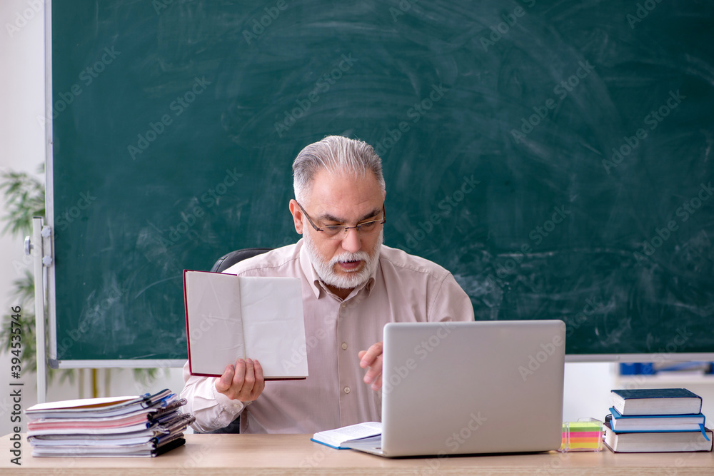 Old male teacher sitting in the classroom Old male teacher sitting in the classroom