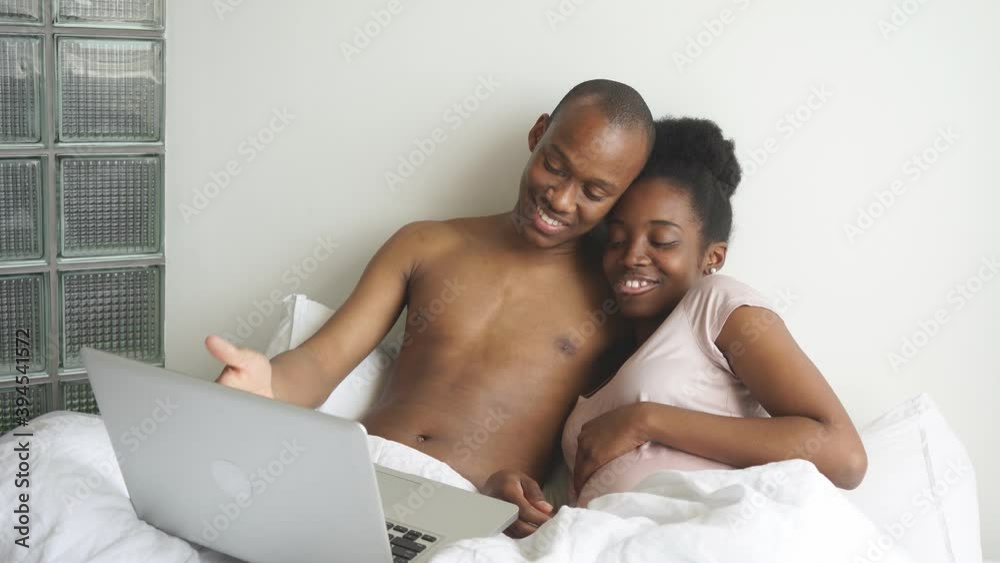 Happy smiling black couple watching film on laptop at home. Happy smiling black couple watching film on laptop at home.