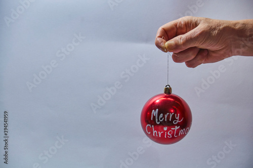 Hand holding a red christmas bulb, written Merry Christmas