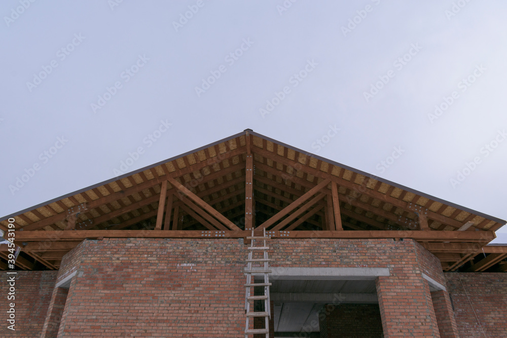 Roof on a brick house. Wooden logs, rafters, racks. Roof construction concept for low-rise construction.