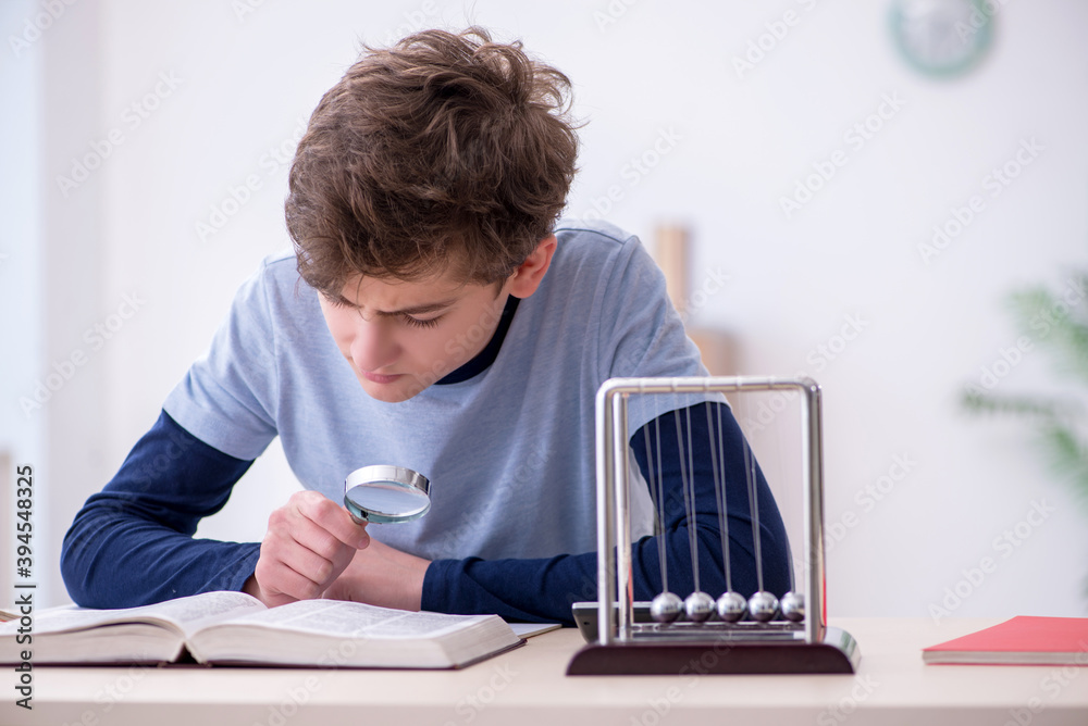 Naklejka premium Schoolboy studying physics at home