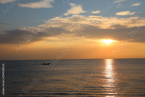 Orange Sunset at dawn with the wide view of sea and small boat floating on the ocean © Snowhite