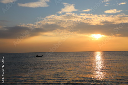 Orange Sunset at dawn with the wide view of sea and small boat floating on the ocean
