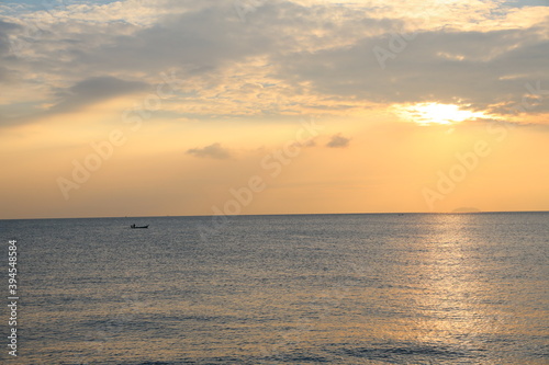 Orange Sunset at dawn with the wide view of sea and small boat floating on the ocean
