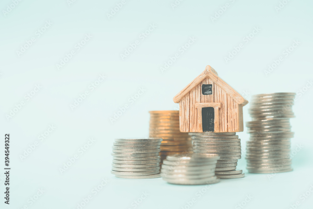 brown miniature house on pile of coins with blue-green background, business and finance background brown miniature house on pile of coins with blue-green background, business and finance background