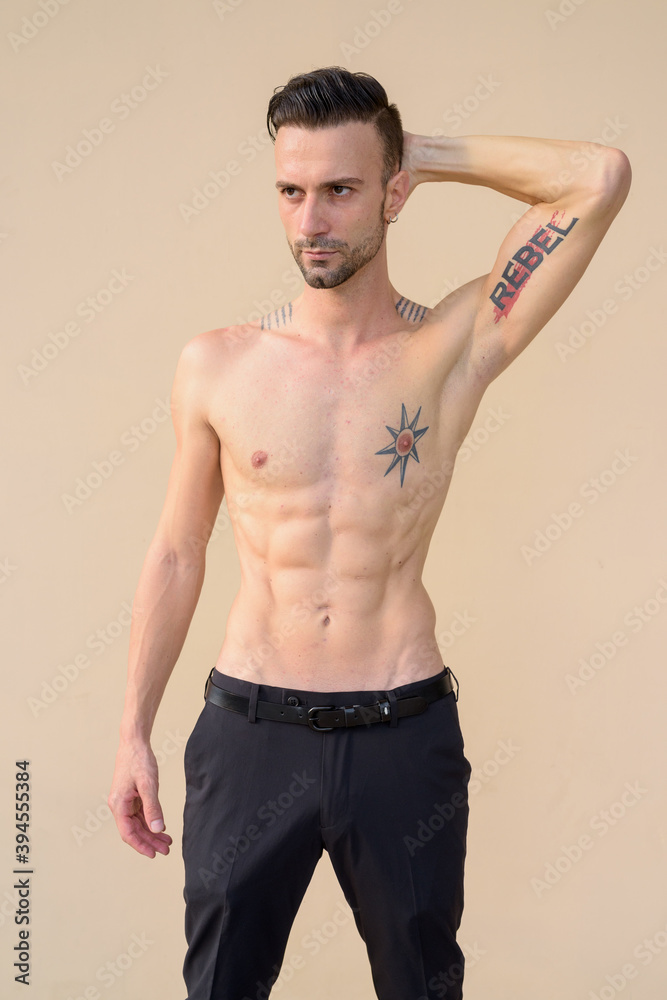 Fototapeta premium Portrait of handsome young man shirtless against wall