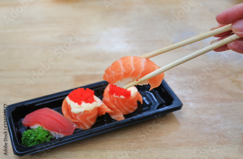 Sushi seafood set in chopsticks on black tray on wood table. Japanese food cuisine