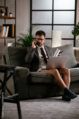 Businessman with no pants working at home. Young man using the laptop having video call.