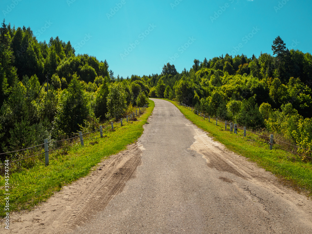 Beautiful landscape view of hillsides and old road at the summertime with forest in vibrant colors.