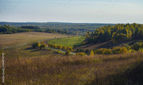 Beautiful landscape view of hillsides and road at the fall time with forest in vibrant colors. © Evgesha