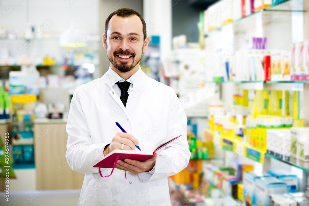 Fototapeta premium Adult male pharmacist checking assortment of drugs in pharmacy