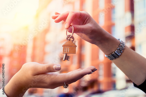 estate agent handing house key for the new owner on home background