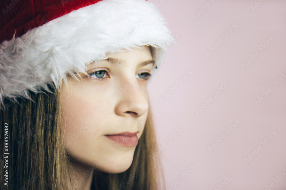 Smiling beautiful girl with long blonde hair in fluffy Santa Claus hat on a pink background. Smiling beautiful girl with long blonde hair in fluffy Santa Claus hat on a pink background.