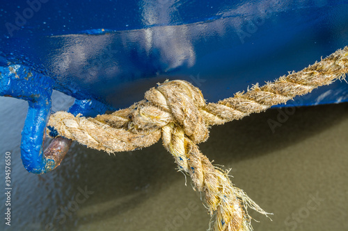 A rope knot hanging on a blue boat. photo