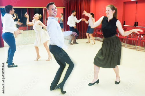 Motion blur of dancing couples enjoying active dance in modern studio