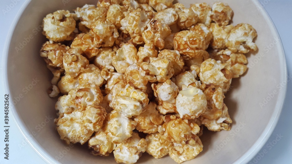 Caramel popcorn in bowl isolated on white background. Popcorn (popped corn, popcorns or pop-corn) is a variety of corn kernel which expands and puffs up when heated. Caramel popcorn in bowl isolated on white background. Popcorn (popped corn, popcorns or pop-corn) is a variety of corn kernel which expands and puffs up when heated.