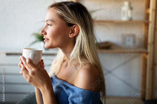 Beautiful young woman enjoying a cup of coffee while relaxing at home.