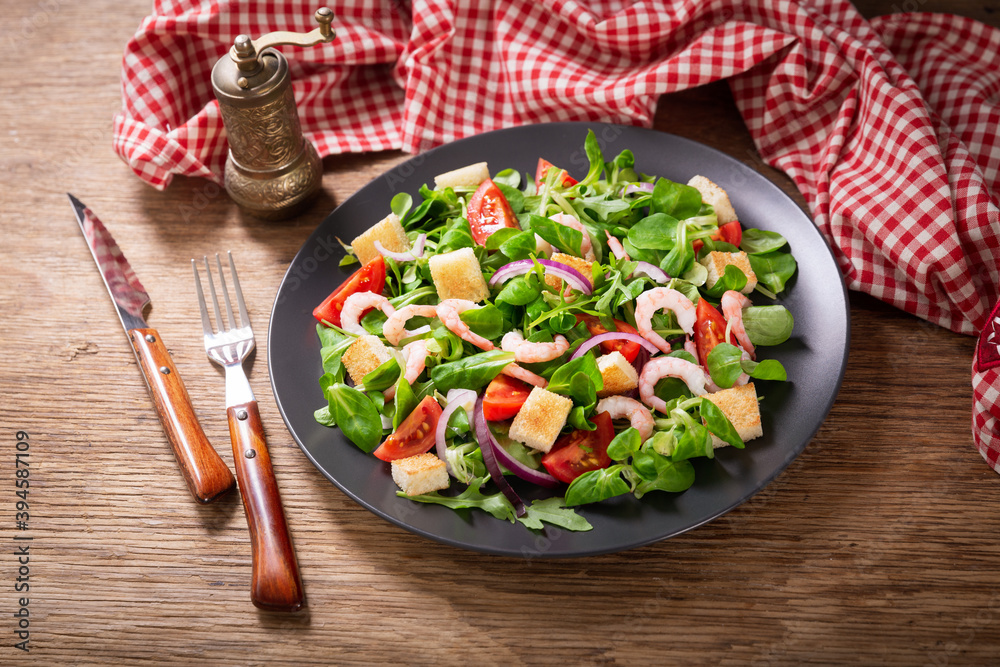 plate of fresh salad with shrimps, greens and tomato