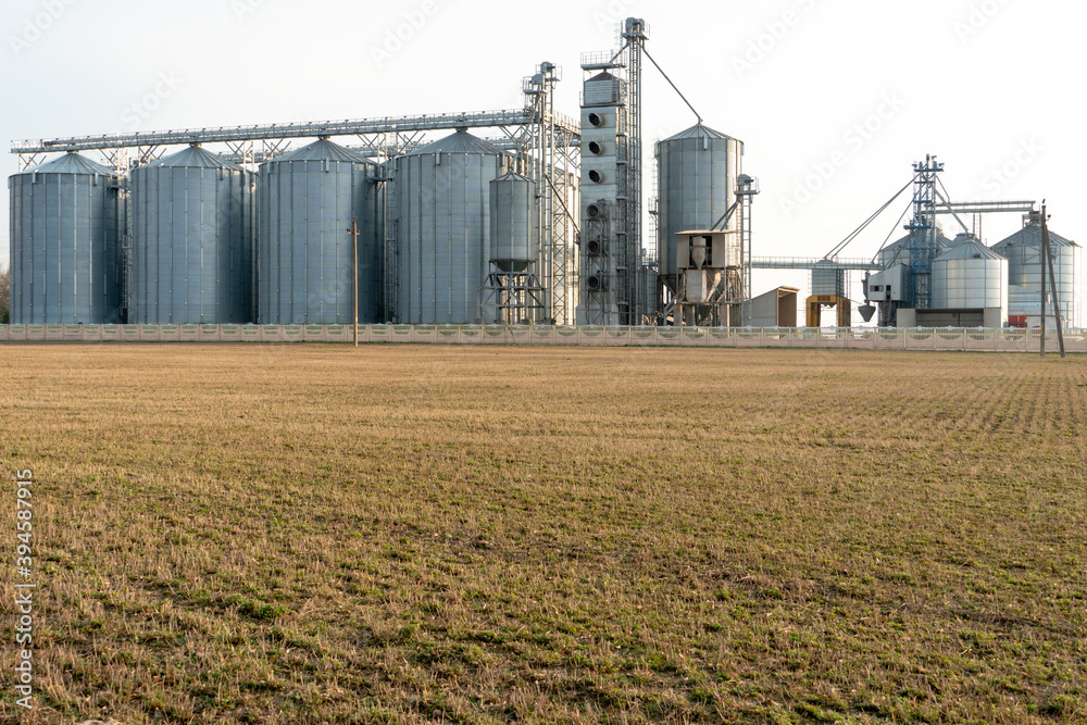 silver silos on agro manufacturing plant for processing drying cleaning and storage of agricultural products, flour, cereals and grain. Large iron barrels of grain. Granary elevator silver silos on agro manufacturing plant for processing drying cleaning and storage of agricultural products, flour, cereals and grain. Large iron barrels of grain. Granary elevator