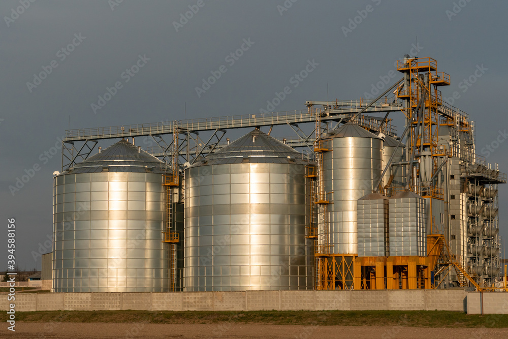 silver silos on agro manufacturing plant for processing drying cleaning and storage of agricultural products, flour, cereals and grain. Large iron barrels of grain. Granary elevator silver silos on agro manufacturing plant for processing drying cleaning and storage of agricultural products, flour, cereals and grain. Large iron barrels of grain. Granary elevator