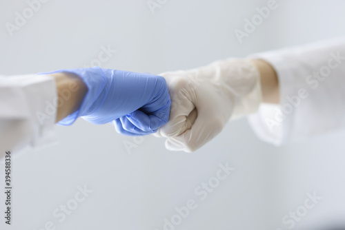 Doctors in rubber gloves touching their fists in clinic close-up. Health care workers cooperation concept © H_Ko