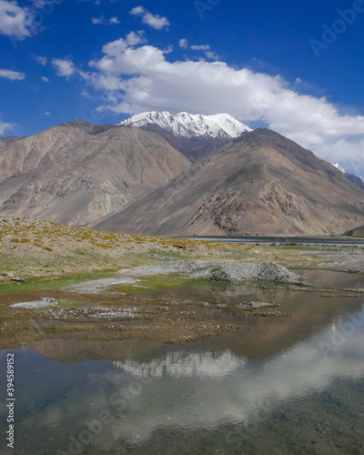View of Hindu Kush snow-capped peak with reflection in water on Afghan side of Panj river valley in Wakhan Corridor  Gorno-Badakshan  Tajikistan Pamir
