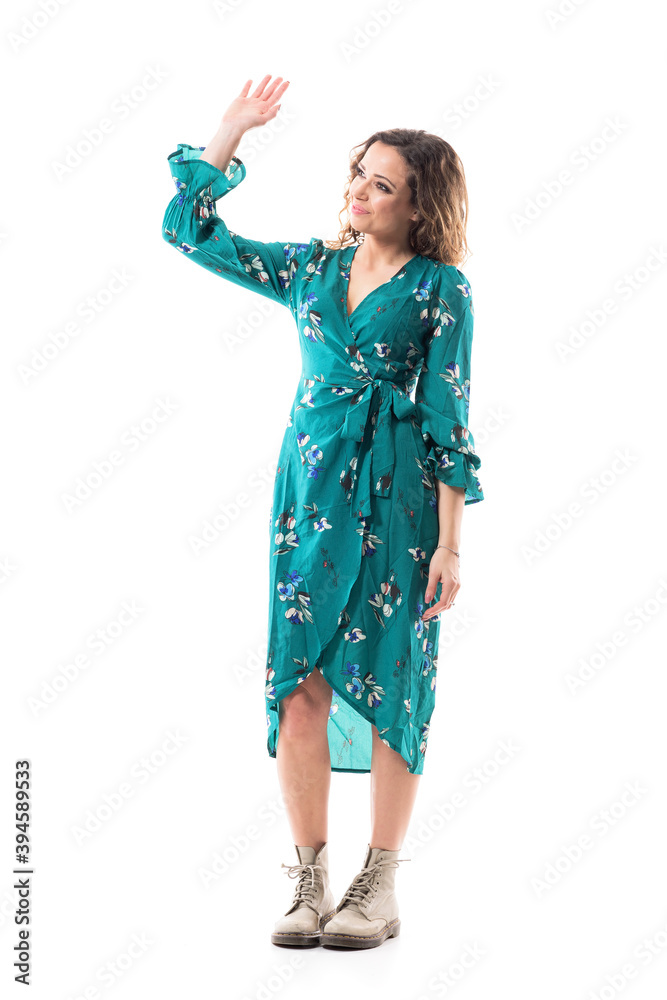 Relaxed beautiful young woman in dress waving hand goodbye saluting looking away. Full body isolated on white background.