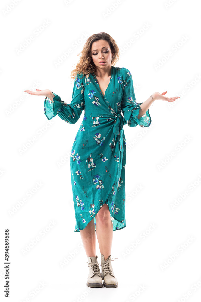 Sad young beautiful woman shrugging with raised hands looking down and apology. Full body isolated on white background.