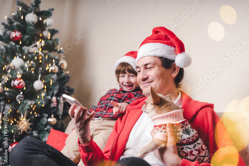 Child with dad and puppy with cell phone at Christmas holidays.
