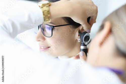 Fotografie Otolaryngologist doctor examining patients ear with otoscope in clinic