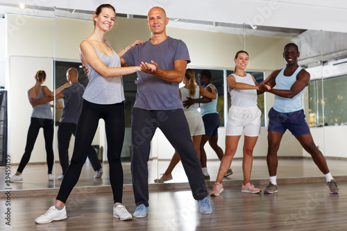Young positive people practicing vigorous jive movements in dance class