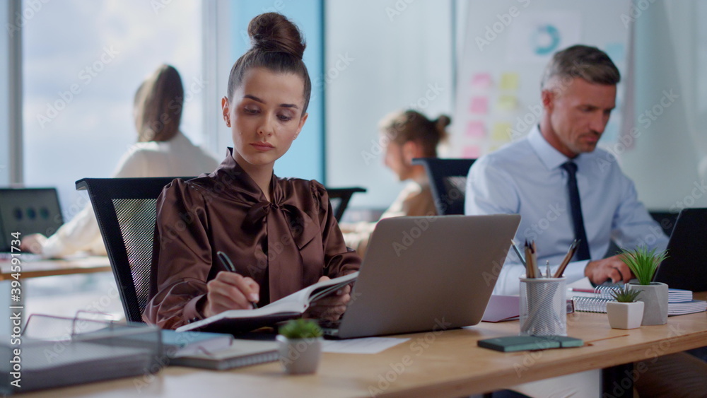 Businesswoman making notes in business diary. Business woman working on laptop Businesswoman making notes in business diary. Business woman working on laptop