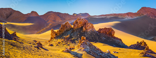 Desert landscape in the Atacama desert with bare rocks and sand dunes in warm late afternoon light photo