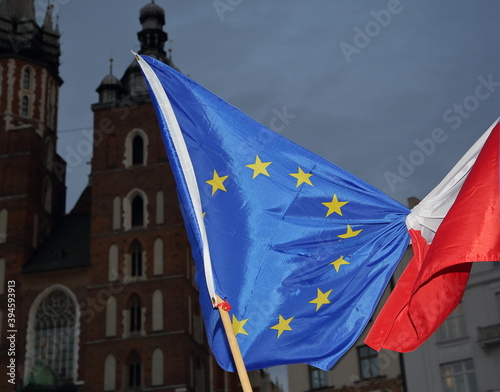 Flag of European Union and Poland tied together on flagpoles in fornt of Saint Marys Church in krakow during pro-EU demonstration in Krakow city center