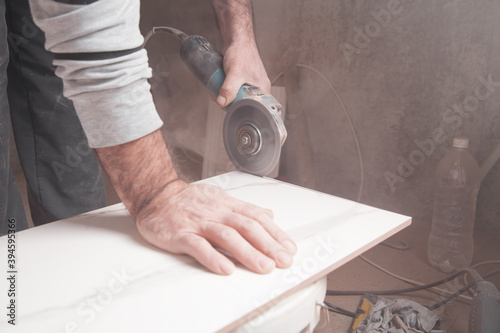 Worker cutting a tile with a grinder.