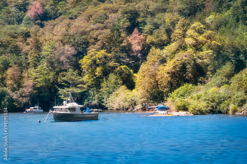 A small helicopter and some boats against the colorful forest at Wanganella Cove at Doubtful Sound on a beautiful summer morning in New Zealand, South Island.