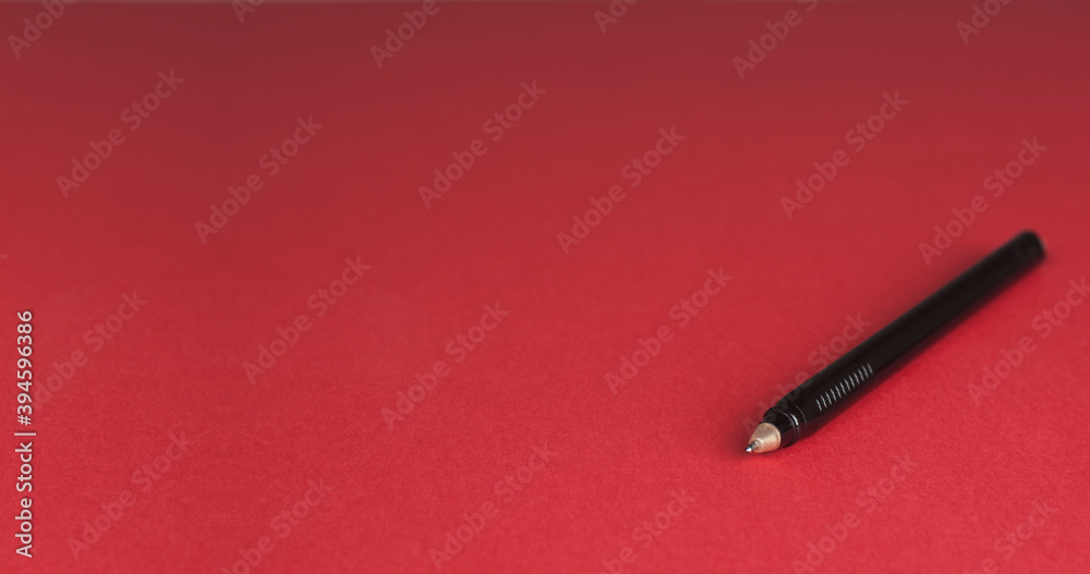 Black pen on a red background. Close-up. Black pen on a red background. Close-up.