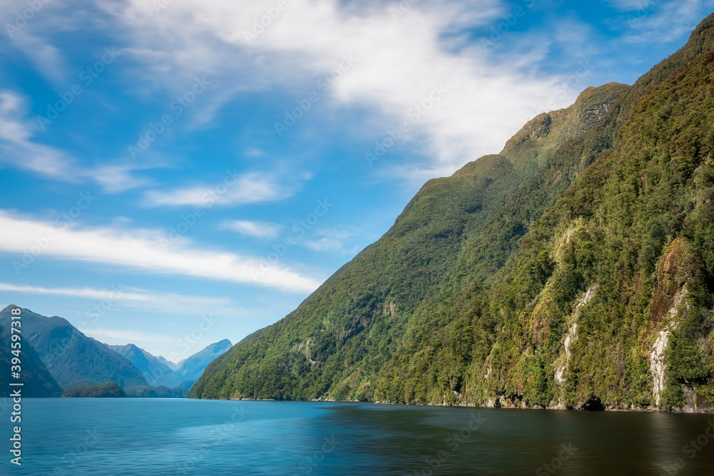 Mountain range covered in rainforest and water views in the remote wilderness of Deep Cove at Doubtful Sound in New Zealand, South Island.