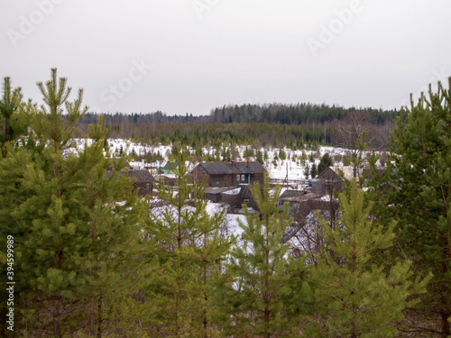 Village is in northern woods of Karelia, winter road with wooden house at evening. Russia