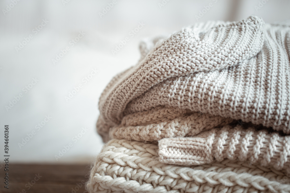 A stack of warm knitted items on blurred white background copy space. A stack of warm knitted items on blurred white background copy space.